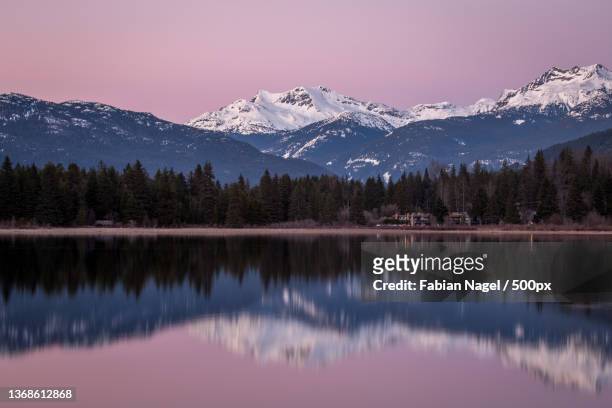 scenic view of lake by snowcapped mountains against sky,whistler,british columbia,canada - whistler winter stockfoto's en -beelden