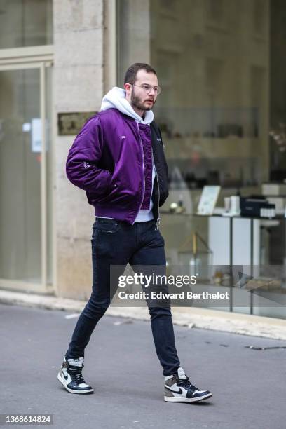 Guest wears glasses, a white hoodie sweater, a half purple and half black zipper bomber coat, black denim jeans pants, black / white / brown shiny...