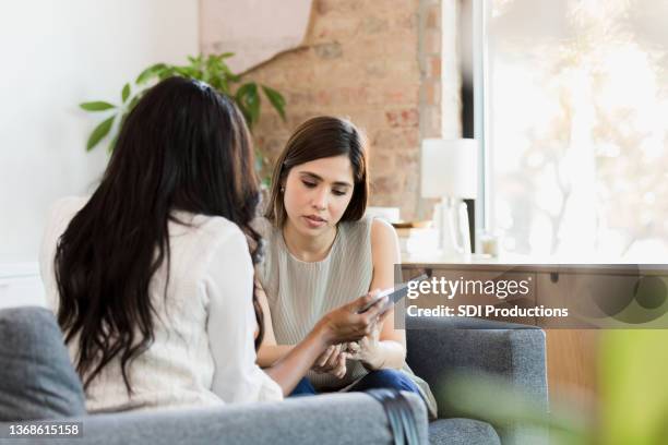 unrecognizable female therapist shows female client app on tablet - showing empathy stock pictures, royalty-free photos & images
