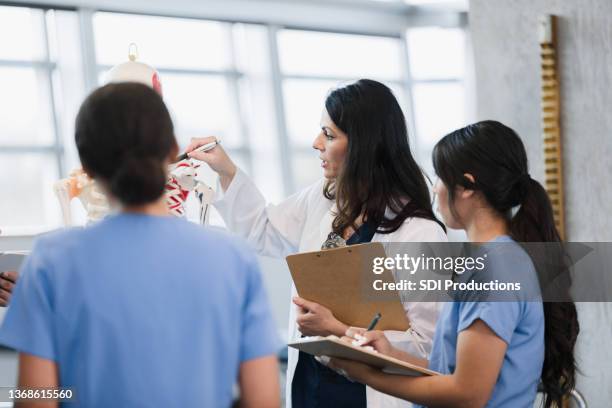 female professor points to human skeleton during lecture - course de skeleton stockfoto's en -beelden