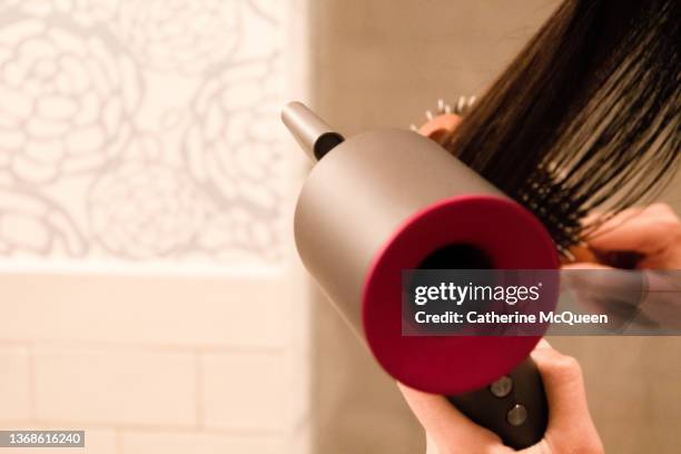 mixed-race teenage girl blow dries her hair at home - haare föhnen stock-fotos und bilder