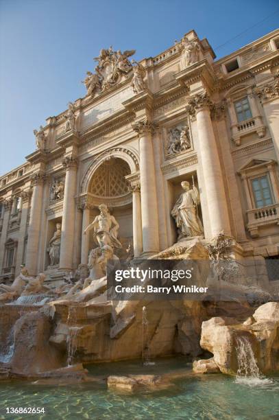 water flowing from sculpture, rocks and building. - fontaine de trévi photos et images de collection