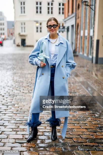 Influencer Influencer Darja Barannik wearing a light blue coat, a white shirt, a light blue blouse, a dark blue flared denim jeans, black ankle boots...