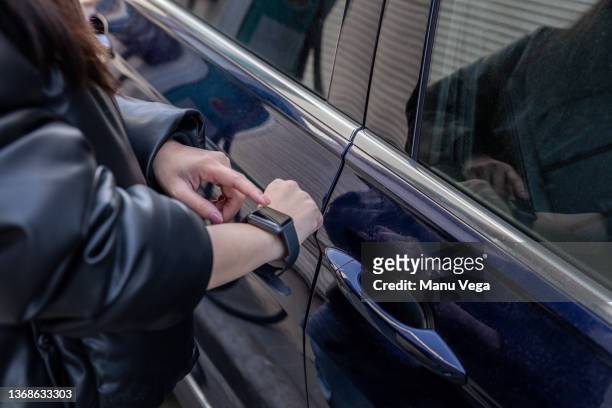 close-up view of a young woman using smart watch to unlock her car - intelligent car stock-fotos und bilder
