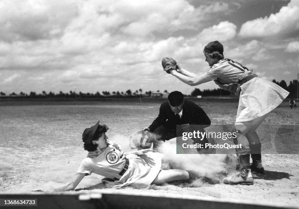 View of on-field action as All-American Girls Professional Baseball Leagues player Margaret 'Marge' Callaghan , of the Fort Wayne Daisies, slides...