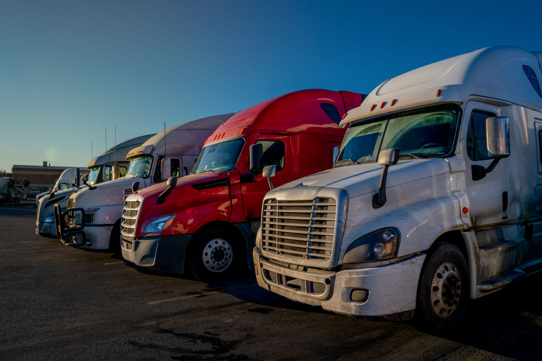 Three Red and White Semi-trucks parked in a lot ready to move cargo across the country Three Red and White Semi-trucks parked in a lot ready to move cargo across the country