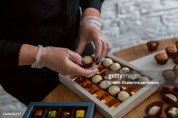 women's hands lay out chocolates in a package. - cacao organization stock pictures, royalty-free photos & images