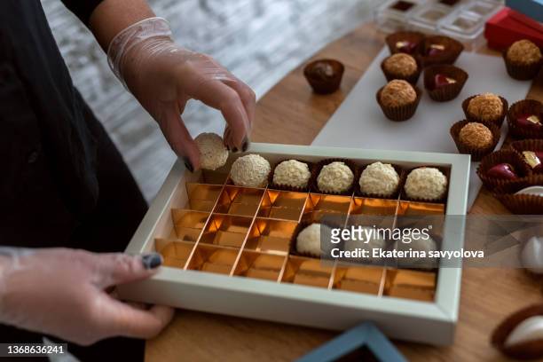 women's hands lay out chocolates in a package. - chocolate box stock-fotos und bilder