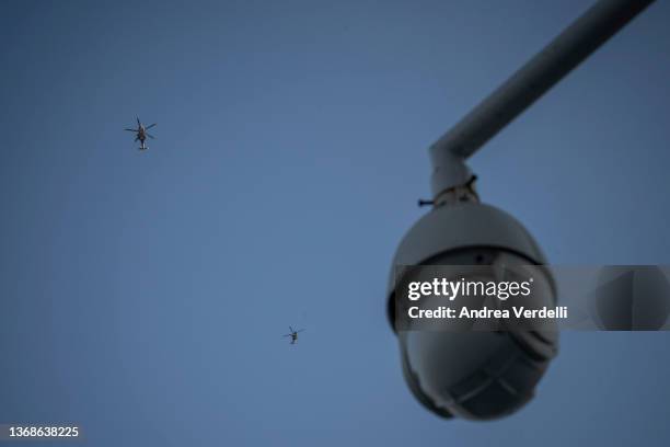 Two police helicopters fly around the National Stadium and a CCTV camera is seen in the background before the opening ceremony of Beijing 2022 Winter...