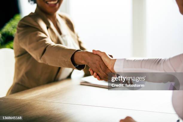 two unrecognizable businesswomen shaking hands after a meeting - hand schudden stockfoto's en -beelden