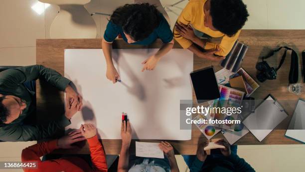 equipe de designers gráficos sentados em uma reunião, desenvolvendo um projeto - estúdio de desenho gráfico - fotografias e filmes do acervo