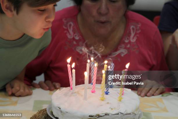 close-up of a senior woman blowing candles on a birthday cake with his grandson behind her - geburtstag 11 stock-fotos und bilder