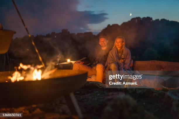 young caucasian couple having quality time next  to a capmfire - warming up stock pictures, royalty-free photos & images