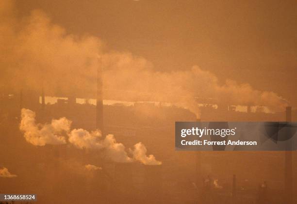 Elevated view, obscured by pollution, of steel factories and smokestacks emitting smoke, Benxi, Liaoning province, China, 1991.