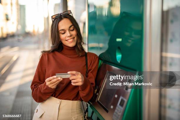 una bella giovane donna preleva denaro in un bancomat - cash withdrawal foto e immagini stock