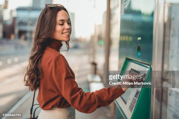 a beautiful young woman withdraws money at an atm - cash in transit stock pictures, royalty-free photos & images