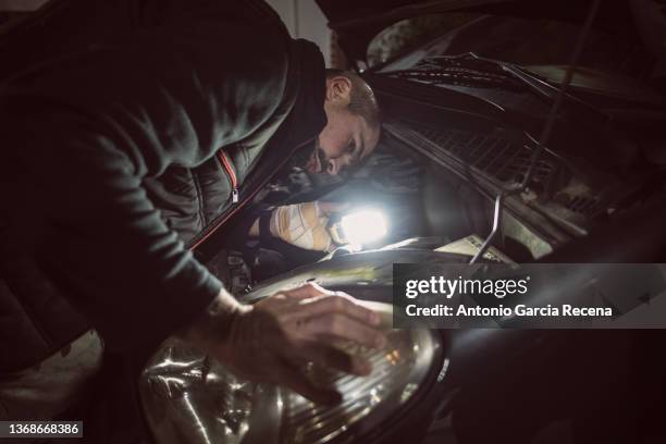 realistic mechanic repair car lights during a night emergency - auto repair shop foto e immagini stock