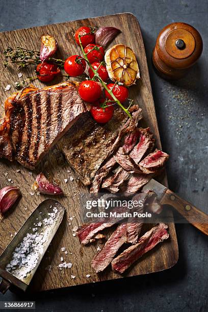 steak cut on board with roasted veg - biefstuk stockfoto's en -beelden