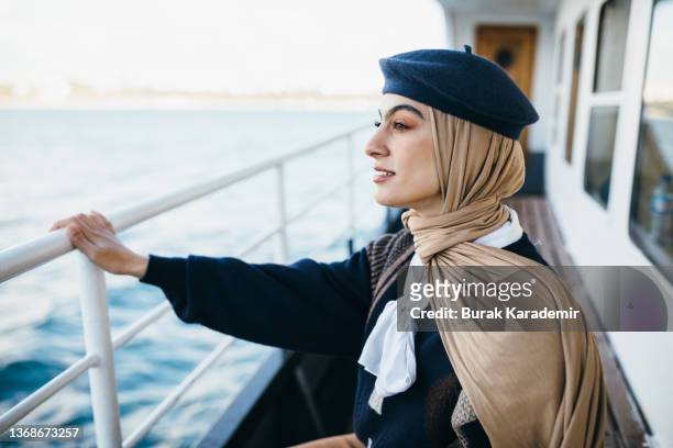 beautiful young muslim woman in hijab rides in the ferry. young female passenger sits in public transport.(daily commute) - contemporary istanbul stock-fotos und bilder