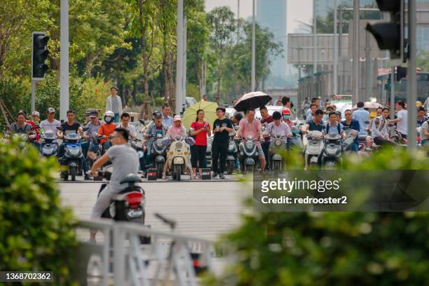 people on electric bikes waiting at traffic light during rush hour - nanning stockfoto's en -beelden