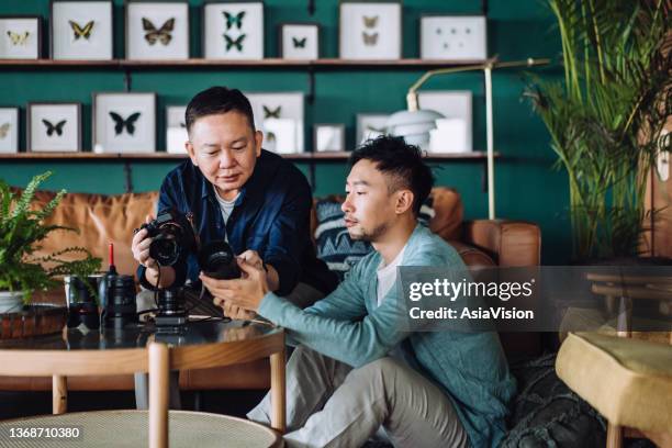 senior asian father and son with their camera and camera lens collection, sharing their common interest and hobbies together at home - old photographer imagens e fotografias de stock