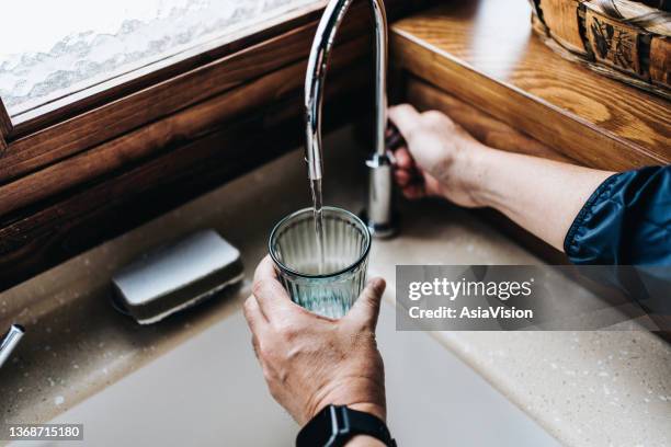 persönliche perspektive des menschen, der ein glas gefiltertes wasser direkt aus dem wasserhahn in der heimischen küche füllt - lap body area stock-fotos und bilder