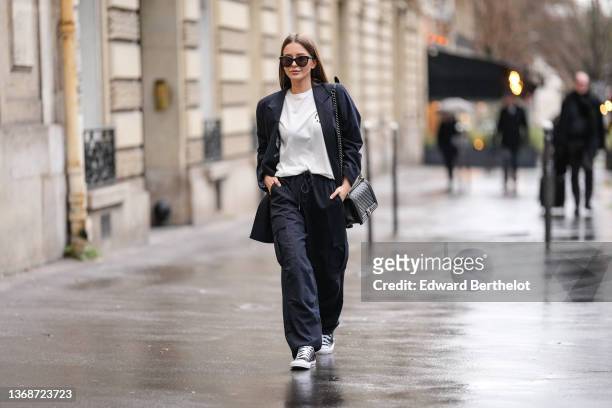 Diane Batoukina wears sunglasses from Chanel, a white t-shirt from Munthe, a navy blue stripped oversized blazer jacket from Munthe, matching navy...