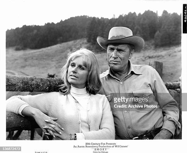 Diana Hyland and unidentified man leaning against ranch post in a scene from the film 'Smoky', 1966.