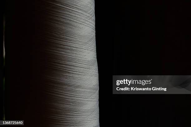 rolls of thread sewing white clothes against a dark background - thread sewing item stock pictures, royalty-free photos & images