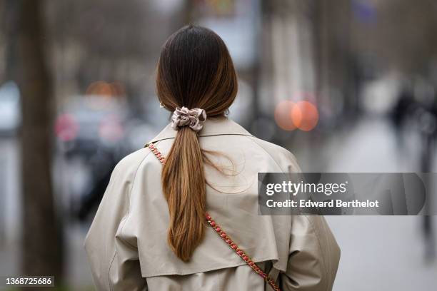 Maria Rosaria Rizzo wears gold large earrings, a beige long trench coat from Max Mara, a pink shiny leather crossbody bag from Moschino, a gold silk...