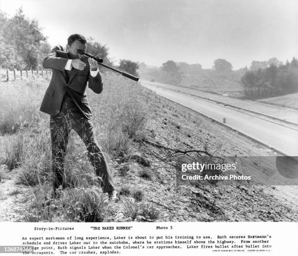 Frank Sinatra aims rifle towards highway in a scene from the film 'The Naked Runner', 1967.