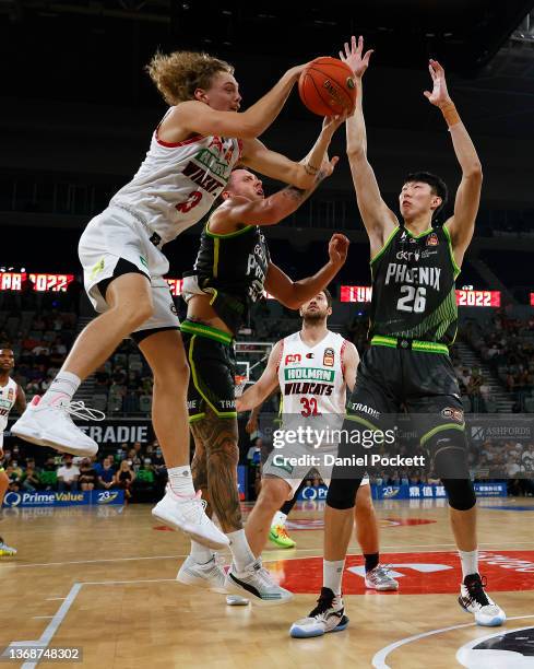 Luke Travers of the Wildcats rebounds the ball against Zhou Qi of the Phoenix and Mitchell Creek of the Phoenix during the round 10 NBL match between...