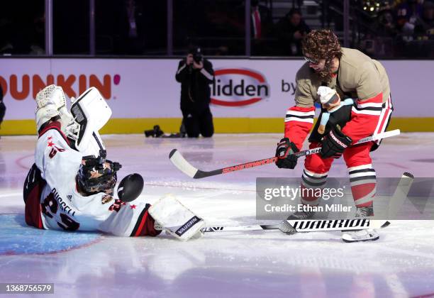 Alex DeBrincat of the Chicago Blackhawks, dressed as Zach Galifianakis' character from The Hangover" movie, shoots a football past actor Wyatt...