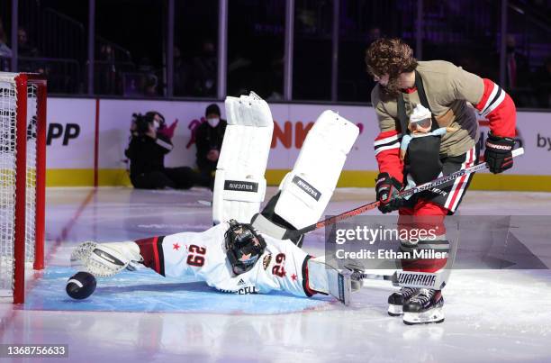 Alex DeBrincat of the Chicago Blackhawks, dressed as Zach Galifianakis' character from The Hangover" movie, shoots a football past actor Wyatt...