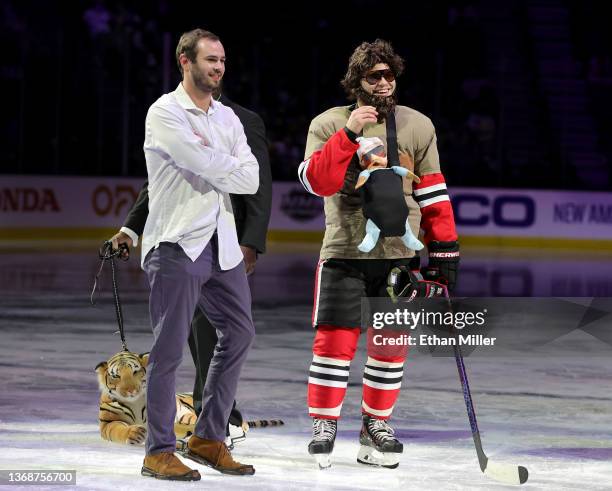 Wide receiver Hunter Renfrow of the Las Vegas Raiders stands on the ice with Alex DeBrincat of the Chicago Blackhawks, dressed as Zach Galifianakis'...