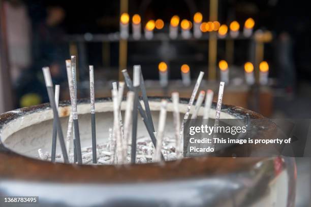 close-up of incense burning in a cauldron on mount misen near miyajima, japan. the flame of some unfocused candles can be seen in the background - shinto stock pictures, royalty-free photos & images