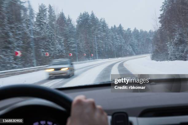 dangerous skid on a slippery snow covered country road. sharp turn of the highway in winter in a forest area. view through the windshield on a moving car - slippery stock pictures, royalty-free photos & images