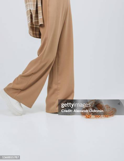 close-up of female legs in pants and boots on a white background in the studio. - beige pants stock-fotos und bilder