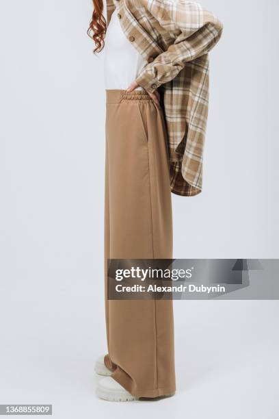 close-up of a woman's legs in pants posing in a new collection of clothes on a white background in a studio photo. - beige pants stock pictures, royalty-free photos & images