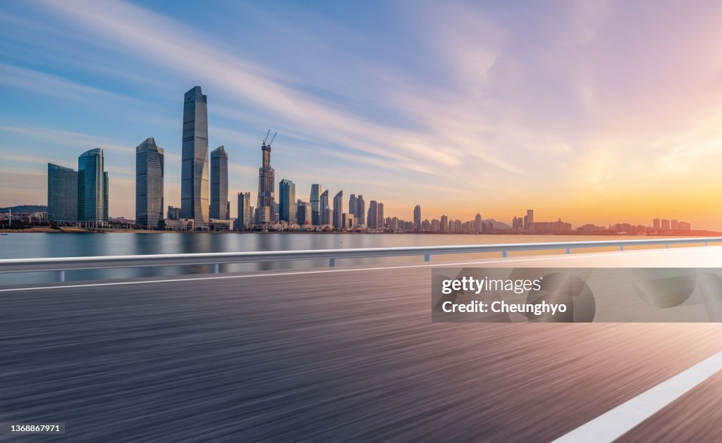 Auto Advertising Backplate. Empty Road in front of Magnificent Sunrise Glow Over Qingdao City Skyline
