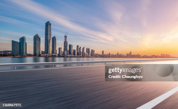 auto advertising backplate. empty road in front of magnificent sunrise glow over qingdao city skyline - urban road stock pictures, royalty-free photos & images