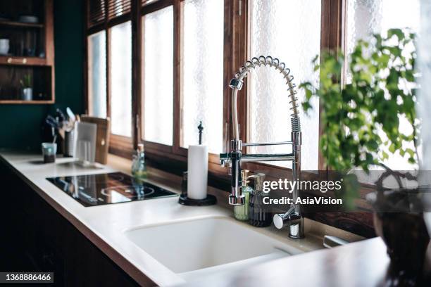 acogedor interior de cocina moderna, con accesorios de cocina y utensilios de cocina. decorado con plantas. luz solar que entra por la ventana - fregadero fotografías e imágenes de stock