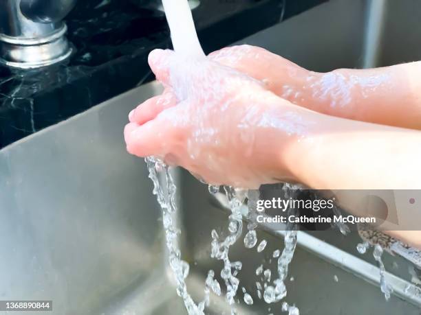 mixed-race young girl washing hands at kitchen sink - washing hands close up stock pictures, royalty-free photos & images