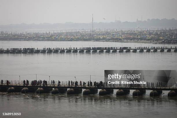 Hindu devotees make their way across pontoon bridges on the Ganges river during month-long annual Magh Mela festival on February 05, 2022 in...