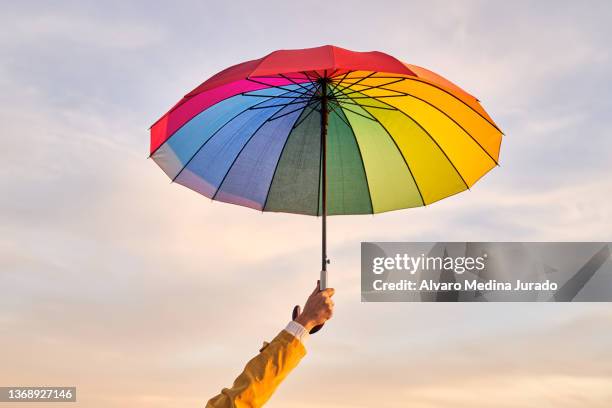 crop person with rainbow umbrella at sunset - meteorología fotografías e imágenes de stock