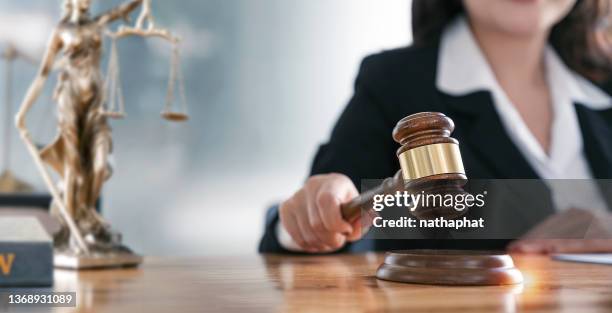 Woman judge hand holding gavel to bang on sounding block in the court room.