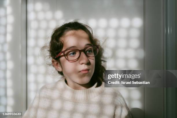 portrait of young caucasian girl with glasses sitting in her room with serious face. - smart glasses stockfoto's en -beelden