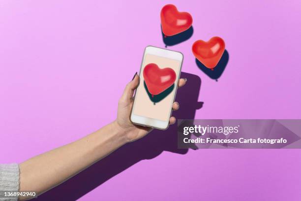 holding a smartphone with red hearts - three objects stock pictures, royalty-free photos & images