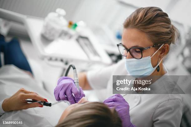 dentist repairing the patient's teeth in the dental office. - dentists stock pictures, royalty-free photos & images