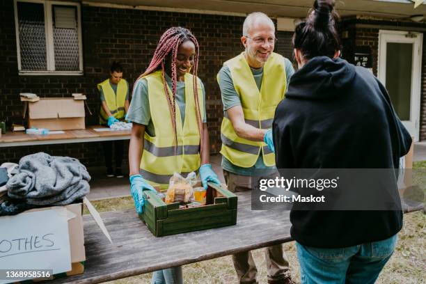 smiling mature male volunteer giving food to woman in community garden - food pantry ストックフォトと画像